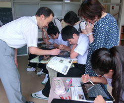 江村教諭(左)の指導で、記事データベースを検索する福山市立山野中の3年生