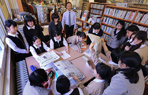 ニュース検定に向け図書館で新聞を読み比べる生徒たち。後列中央が北川孝博教諭、左隣が新田裕子司書