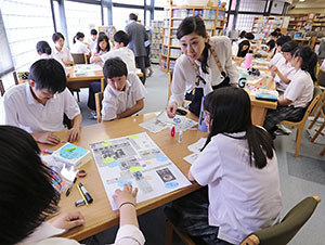 壁新聞を仕上げる生徒たちに助言する梅津麻紀教諭＝１２日、札幌創成高