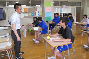 新聞記事を使って授業を進める山田耕平教諭と３年生の生徒たち