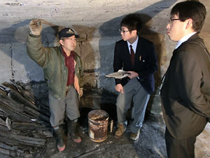 炭焼き窯は落田さん（左）の手作り。熱心に話に聞き入る豊岡さん（中央）と小山教諭