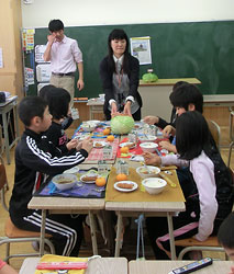 給食指導で和寒の「越冬キャベツ」を子どもたちに示す佐藤教諭（中央）。左は加藤教諭