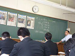 琉球新報の号外を黒板に張り、時事問題研究の授業をする毛利教諭（右） 