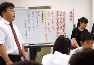 日豪EPAに関する北海道新聞の社説(社説A)の論点を書き出しながら授業を進める腰山潤教諭(左端)