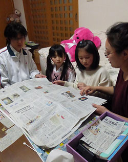 家族４人で新聞を読む鎌田さん一家。父慎一さん（左）と母幸子さん（右）も加わり大事な夜のひとときだ