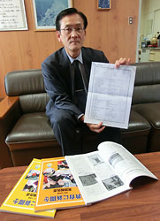 「札幌市小学校ＮＩＥ計画表」の原案を手にする上村副会長。手前の報告書に収められた実践との関連を示すことも検討している