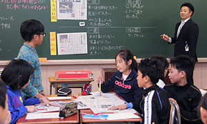 二つの新聞を貼り出して授業を行う内海良亮教諭（神戸新聞社提供