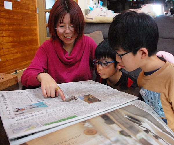 自宅の居間で新聞を囲む（左から）佳代さん、多喜司さん、龍之介さん