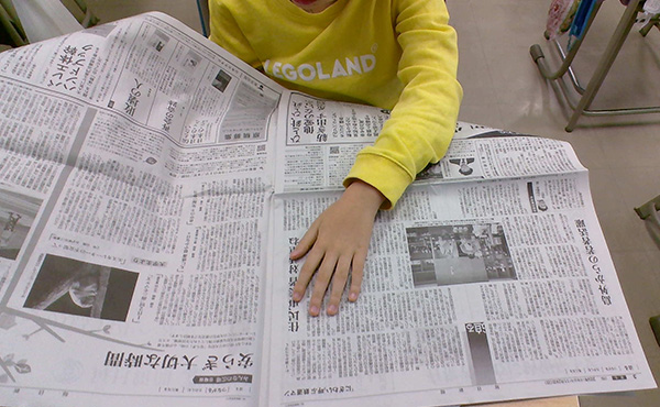 新聞を手にして見やすさを調べる児童