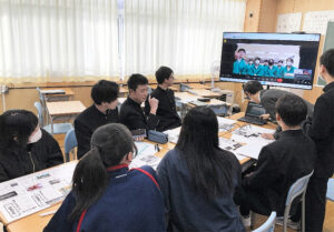 互いの地域を紹介した新聞を前に中郷中の生徒とオンラインで交流する南茅部中の生徒たち＝昨年１２月